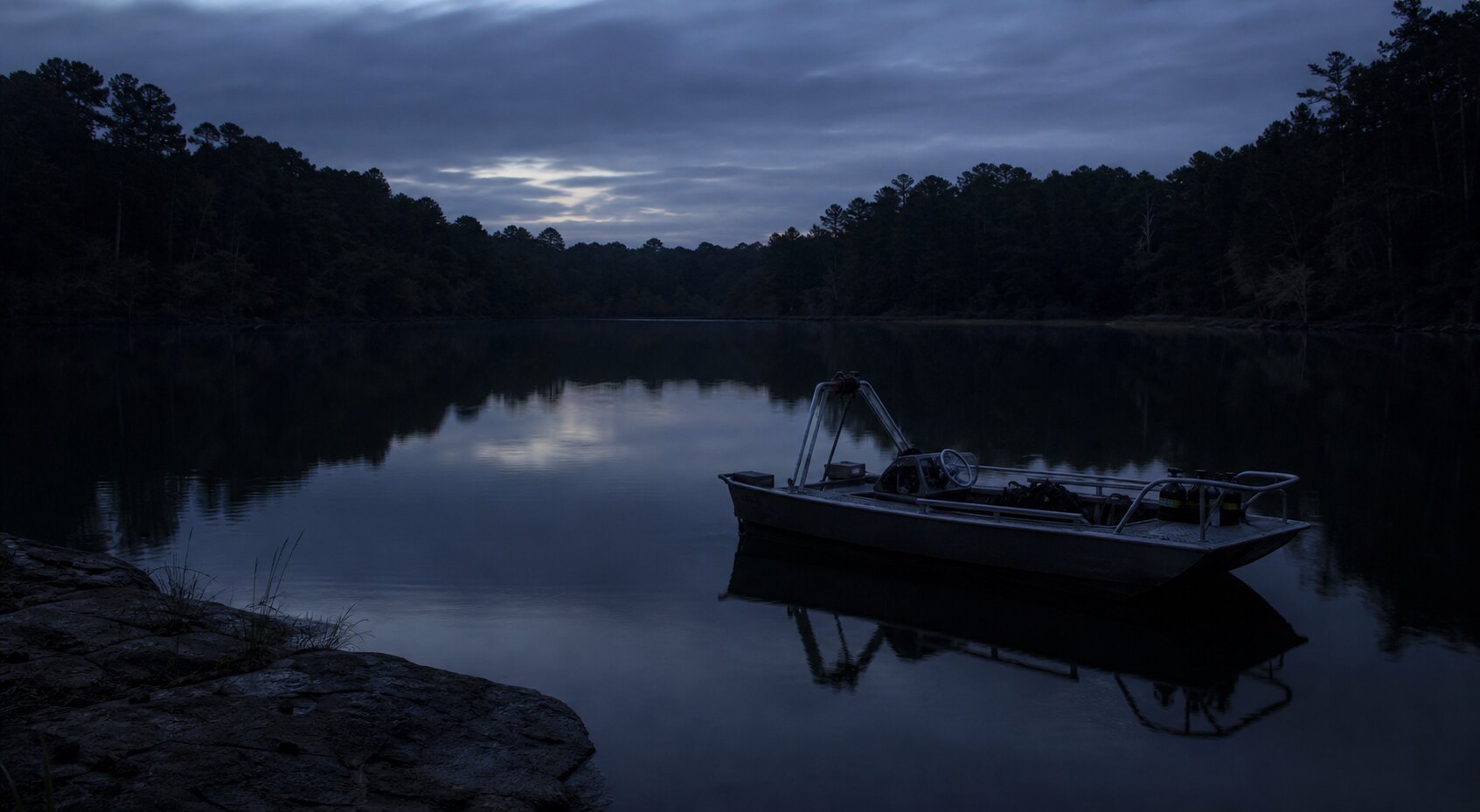 A quiet Texas lake at twilight with a small dive boat evokes the Benbrook Lake search efforts in the Fort Worth Missing Trio case.