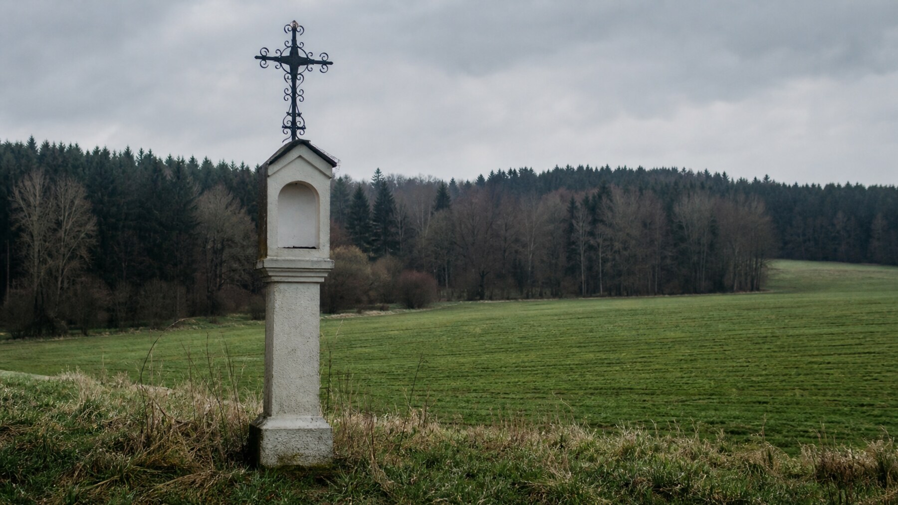 A quiet Bavarian memorial cross in a field reflects the enduring memory of the Hinterkaifeck victims.