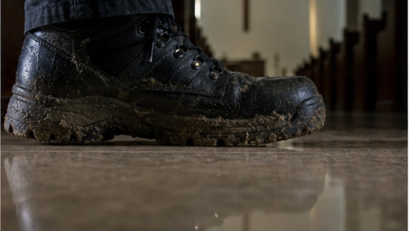 A muddy black tactical boot on a polished church floor, representing the gait and disguise questions in the Missy Bevers investigation.