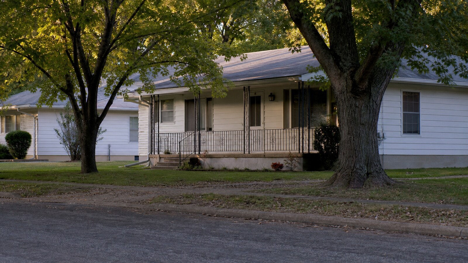A quiet Springfield residential porch seen from across the street in soft afternoon light