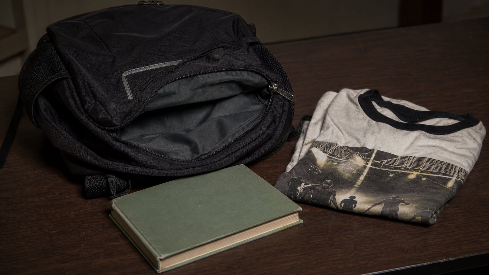 Documentary recreation of a black backpack, generic library book, and vintage shirt connected to the Asha Degree case.