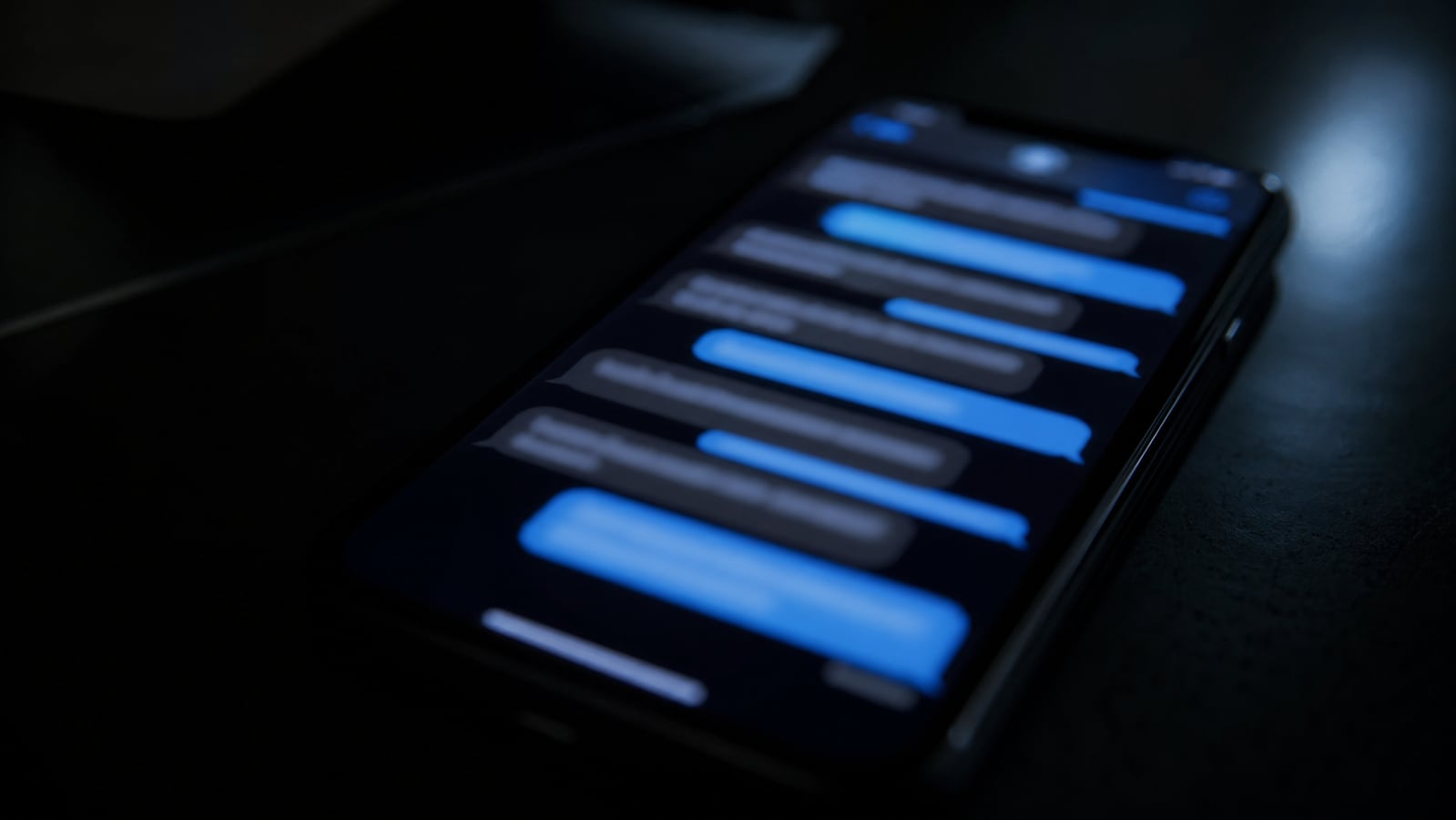 Unreadable smartphone message bubbles in a dark room, representing warrant-reported text messages in the Asha Degree investigation.