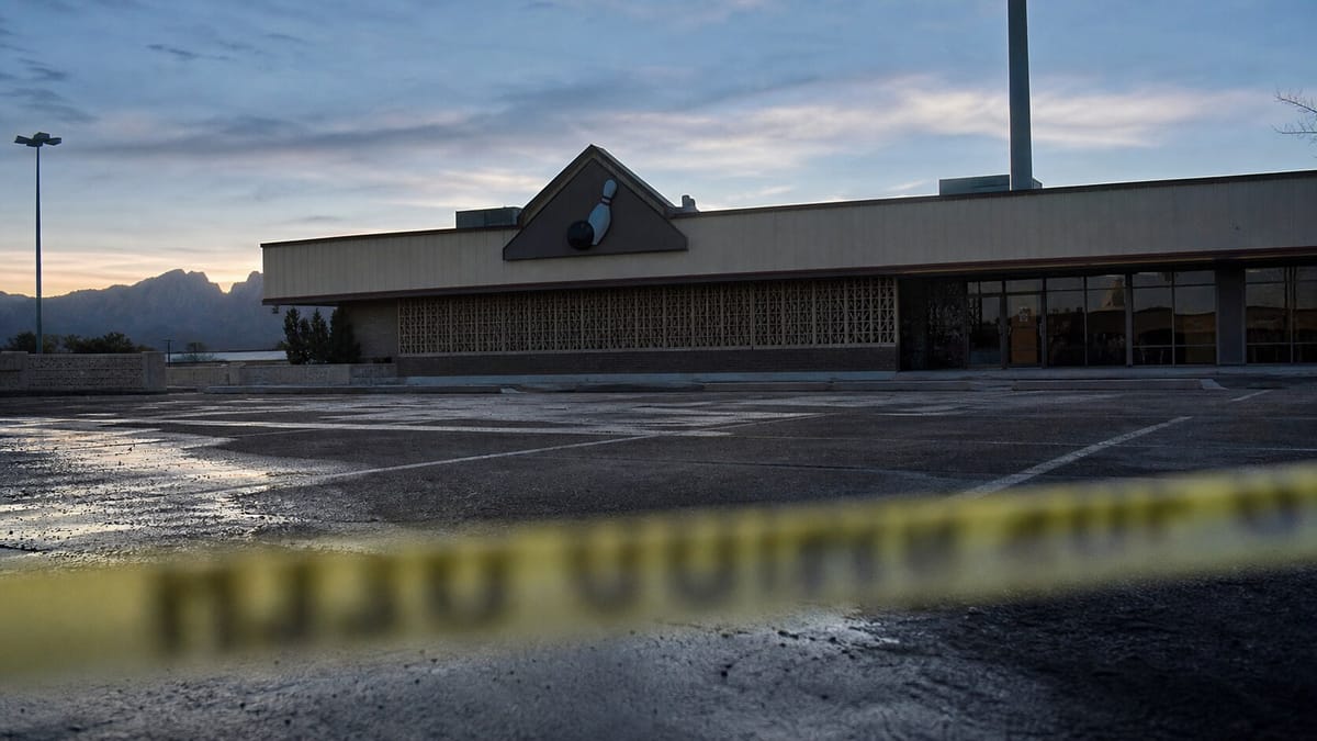 A documentary recreation of the Las Cruces Bowl exterior at dawn with blurred police tape in the foreground.