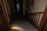 A carpeted staircase with a yellow notepad resting on a lower step, representing the JonBenét Ramsey ransom note.