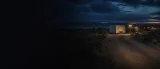 Remote New Mexico property with a closed utility trailer illuminated by investigators at dusk
