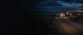 Remote New Mexico property with a closed utility trailer illuminated by investigators at dusk