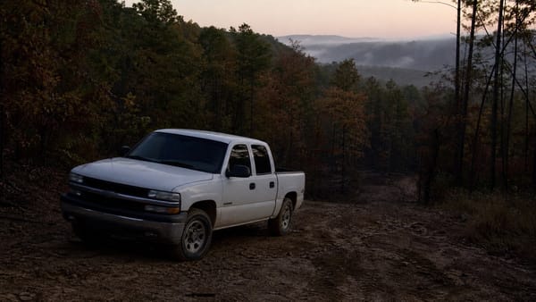 A white pickup truck on a remote wooded Oklahoma dirt road, representing the Jamison family disappearance.