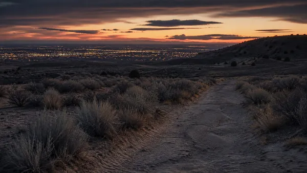 A desolate Albuquerque West Mesa desert trail at dusk, representing the unsolved West Mesa murders.